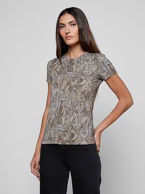 A woman with long brown hair wears the Ressi Fitted Tee with a brown and blue paisley print, paired with black jeans, standing against a plain light gray background with one hand on her hip.