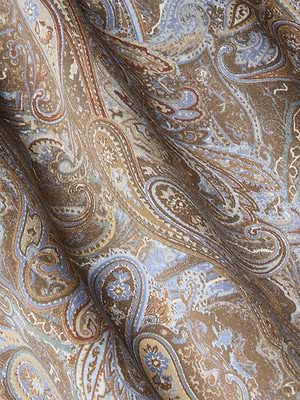 The Seridie Silk Slip Dress features soft brown fabric with an intricate paisley print in blue, beige, and cream. Its rich, swirling design and gentle drape highlight the dress’s detailed texture—ideal for an elegant slip dress style.