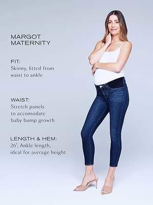 A pregnant woman in a white tank top and dark skinny maternity jeans poses, smiling, with one hand on her bump. Text beside her describes the jeans skinny fit, stretch panels, and 26-inch ankle length for average height.