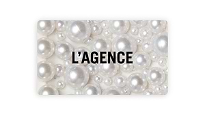 A backdrop of lustrous white pearls of assorted sizes features “L’AGENCE” in bold black caps at the center, showcasing the L'AGENCE Gift Card delivered via email.